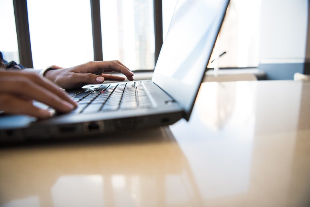 Person writing on a laptop in a bright room