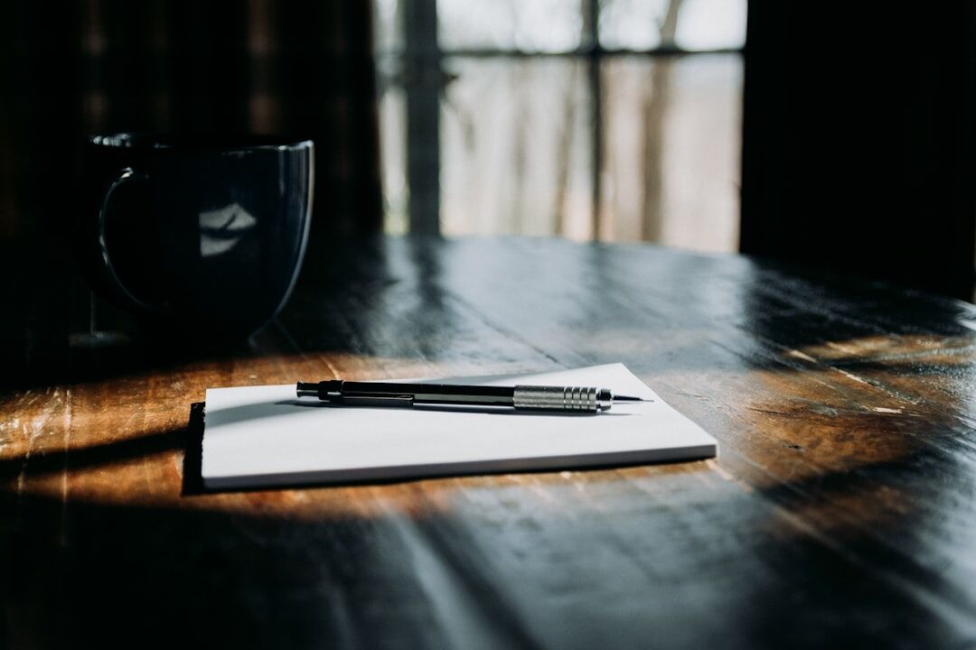 Open notebook with a pen and a cup of tea on a table